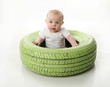 © blessings - Baby sitting inside a bright painted tire