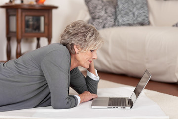 Poster - moderne seniorin mit notebook im wohnzimmer