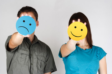 man and woman holding paper cards with sad and fun smiles