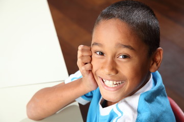 Wall Mural - Laughing young school boy 9 sitting to his classroom desk