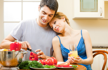 Wall Mural - Young happy smiling couple cooking together at home