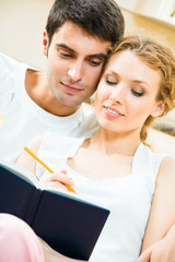 Wall Mural - Young attractive couple with notebook or organizer at home