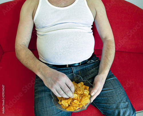 Fat Man On Red Couch Eating Potato Chips Buy This Stock Photo