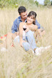 © .shock - happy couple enjoying countryside picnic in long grass