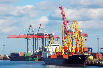 Container stacks and ship under crane bridge