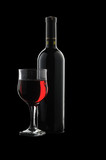 Fototapeta Panele - A glass of red wine and a bottle on a black background