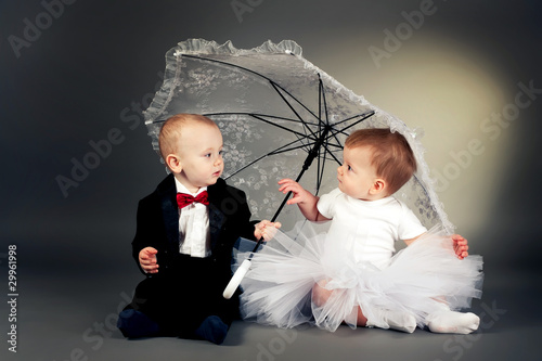 maly-smieszny-chlopiec-i-dziewczynka-siedzi-pod-parasolem