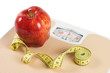 © Vladimir Voronin - Scale, tape and apple on white background