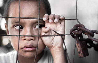 Wall Mural - boy behind fence in Asia depicting poverty - focus on hand