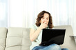 © Sunny_baby - Young Woman on Couch with Laptop