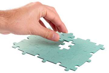 Hand inserting missing piece of green jigsaw puzzle into the hol