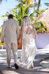 Poster - bride groom walking back tropical setting