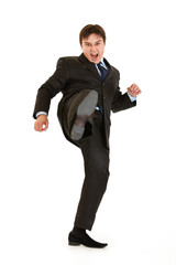 Very angry young businessman hard kicking isolated on white.