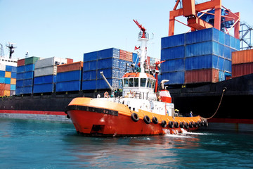 tug boat pulling out container ship