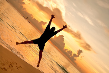 Wall Mural - Man jumps in front of sunset on the ocean