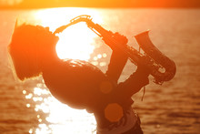Saxophone Music. Woman Playing Sax At Sunset Beach.