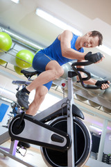 Cycling fit man on spinning bike in gym