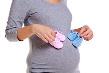 Pregnant Woman Holding Baby Booties.