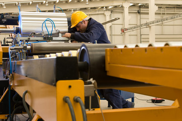 Worker using steel coil processing machine focus on worker.