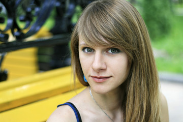 Portrait of a young beautiful blonde in yellow bench in the park