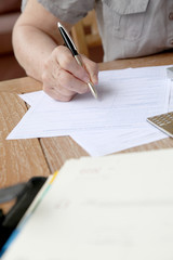 Closeup of senior woman filling in tax form