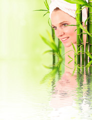 Beautiful woman among bamboo trees with water reflection