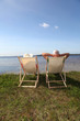 Senior couple in deck chairs in front of a lake