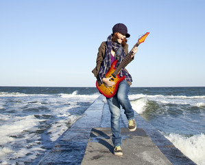 Poster - Young red-haired girl play on guitar at windy day.