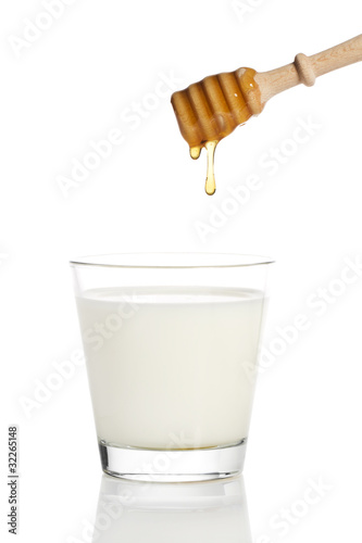 Fotografie, Obraz honig tropft von einem honiglöffel in ein glas milch