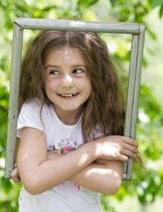 Wall Mural - little girl looking throgh wooden frame - beautiful nature backg