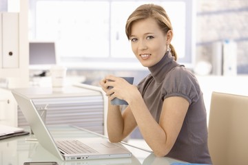 Wall Mural - Young businesswoman drinking tea in office