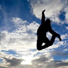 Wall Mural - silhouette of girl jumps in cloudy sky