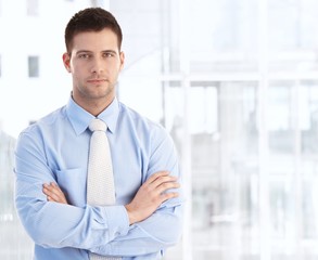 Wall Mural - Young businessman standing arms crossed