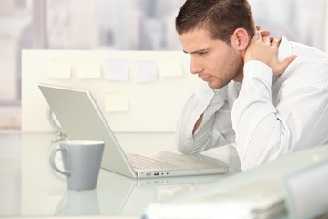 Canvas Print - Young man looking tired in office