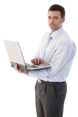 Wall Mural - Casual office worker standing with laptop in hands