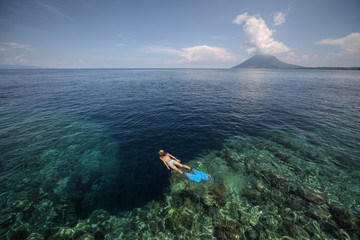 Sticker - Young woman snorkeling over a coral reef in the transparent tropical sea. Bunaken island. Indonesia