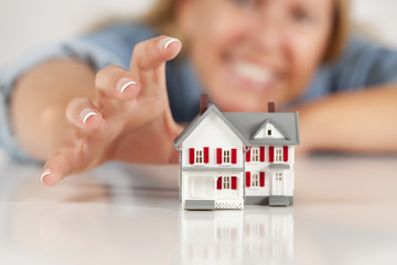 Wall Mural - Smiling Woman Reaching for Model House on White