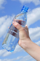  Water bottle in a hand against the sky