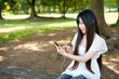 © taka - beautiful asian woman using a smartphone in the park