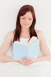 © WavebreakmediaMicro - Beautiful red-haired female reading a book while sitting on her