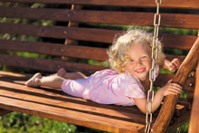 Cute Little Girl With Blond Curly Hair Playing On Wooden Chain S