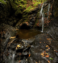 A Small Waterfall Trickles Down A Cliff In Autumn