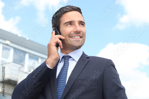 Fotografía Property salesman stood outdoors with mobile telephone