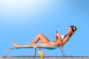 Wall Mural - Woman sunbathing and reading her text messages