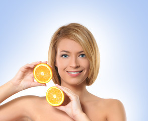 Portrait of a young woman playing with two pieces of a orange