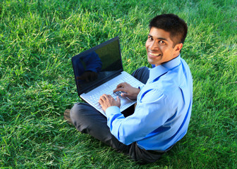 Wall Mural - smiling businessman with laptop at the park