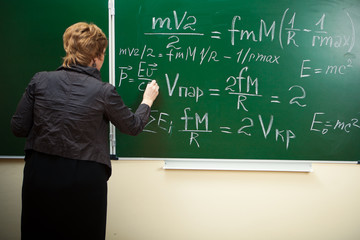 math teacher writing formula on the blackboard