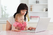 © WavebreakmediaMicro - Attractive brunette woman showing her laptop to her baby while s