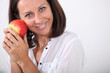 © auremar - Smiling woman holding an apple to her face