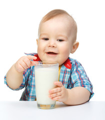 Cute little boy is holding big glass of milk